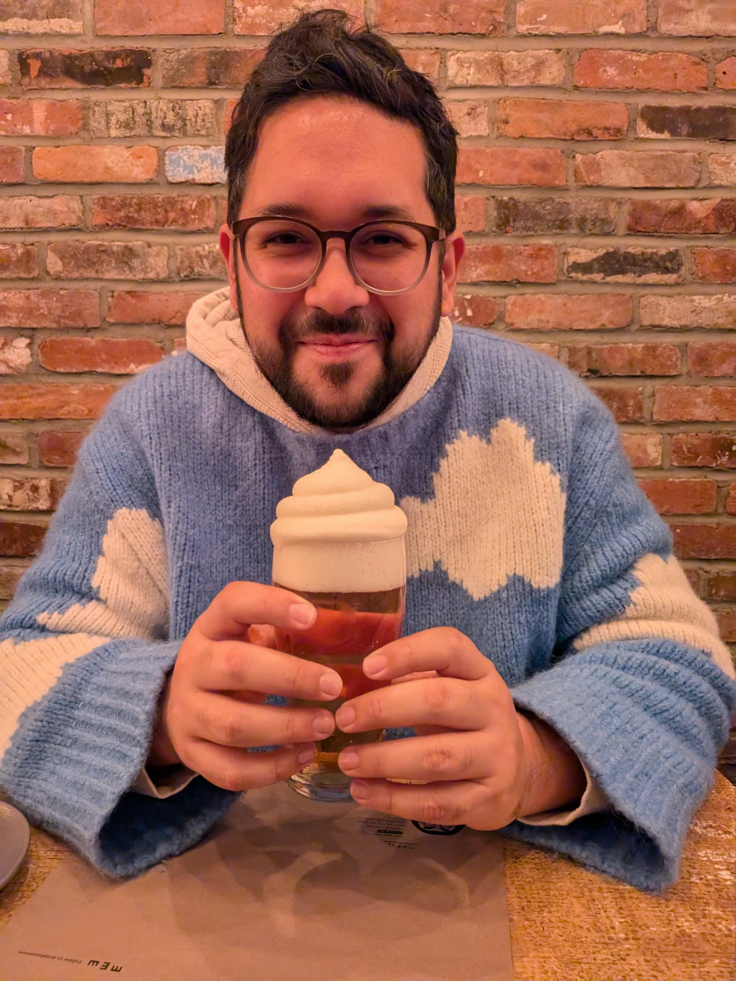 Juan in a blue cloud sweater holding a fancy drink